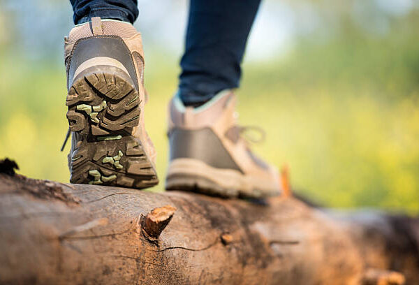 Close up outdoor shoes of a female hiker walking on log.