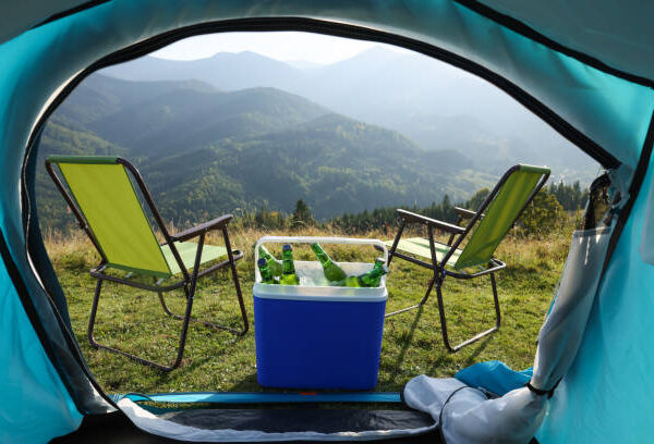 Chairs and cool box with bottles of beer in mountains, view from tent