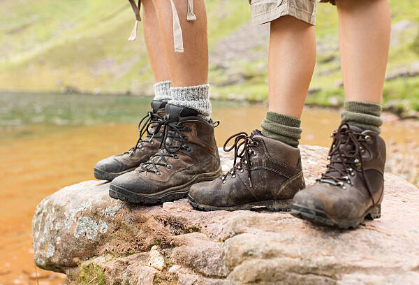Low section of hikers in hiking boots atop rock. Horizontal shot.