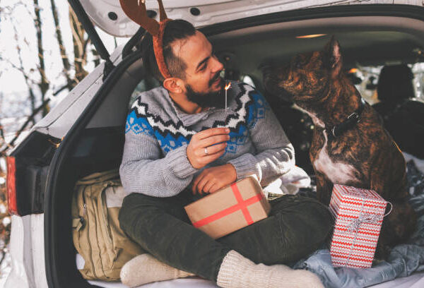 Bearded man and his dog celebrating Christmas in the car.