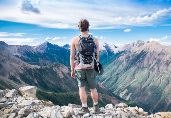 man-standing-on-top-of-mountain-with-backpack